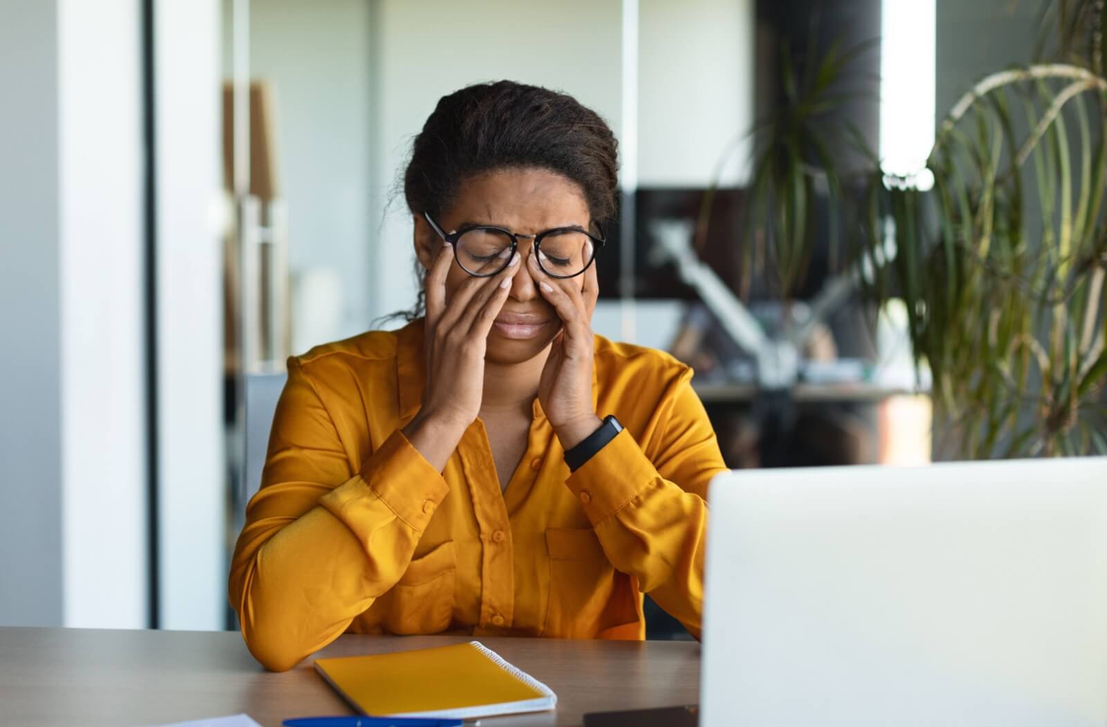 A young woman trying to work at her computer but struggling from blurry vision due to her dry eye.