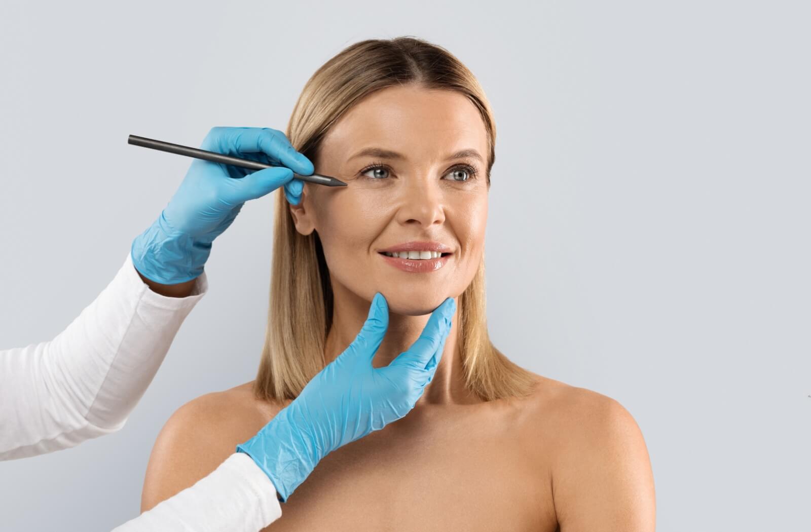 An adult gets their face marked with a pen before getting a non-surgical face lift.
